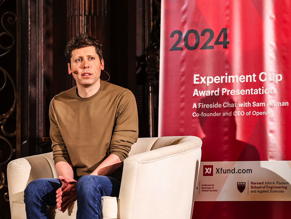 Sam Altman seated beside a 2024 Xfund Experiment Cup banner at a Harvard fireside chat